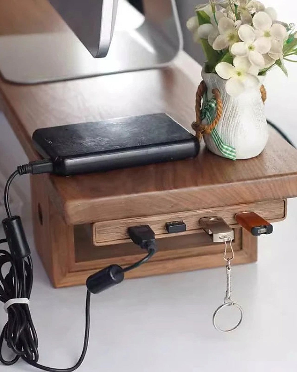 A walnut under-desk hub dock mounted beneath a desk, charging a phone