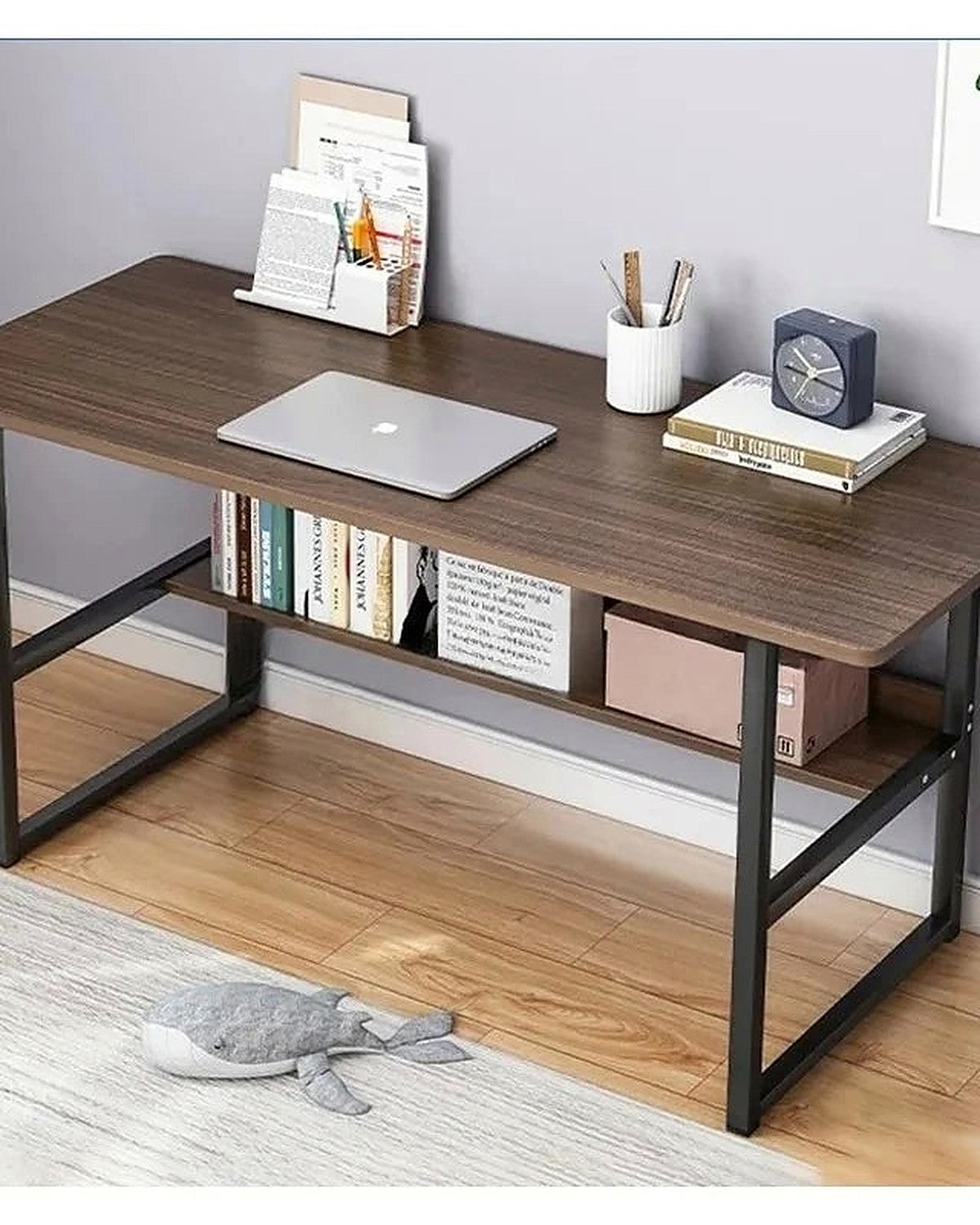 A dark walnut study desk holding a laptop, books and a clock