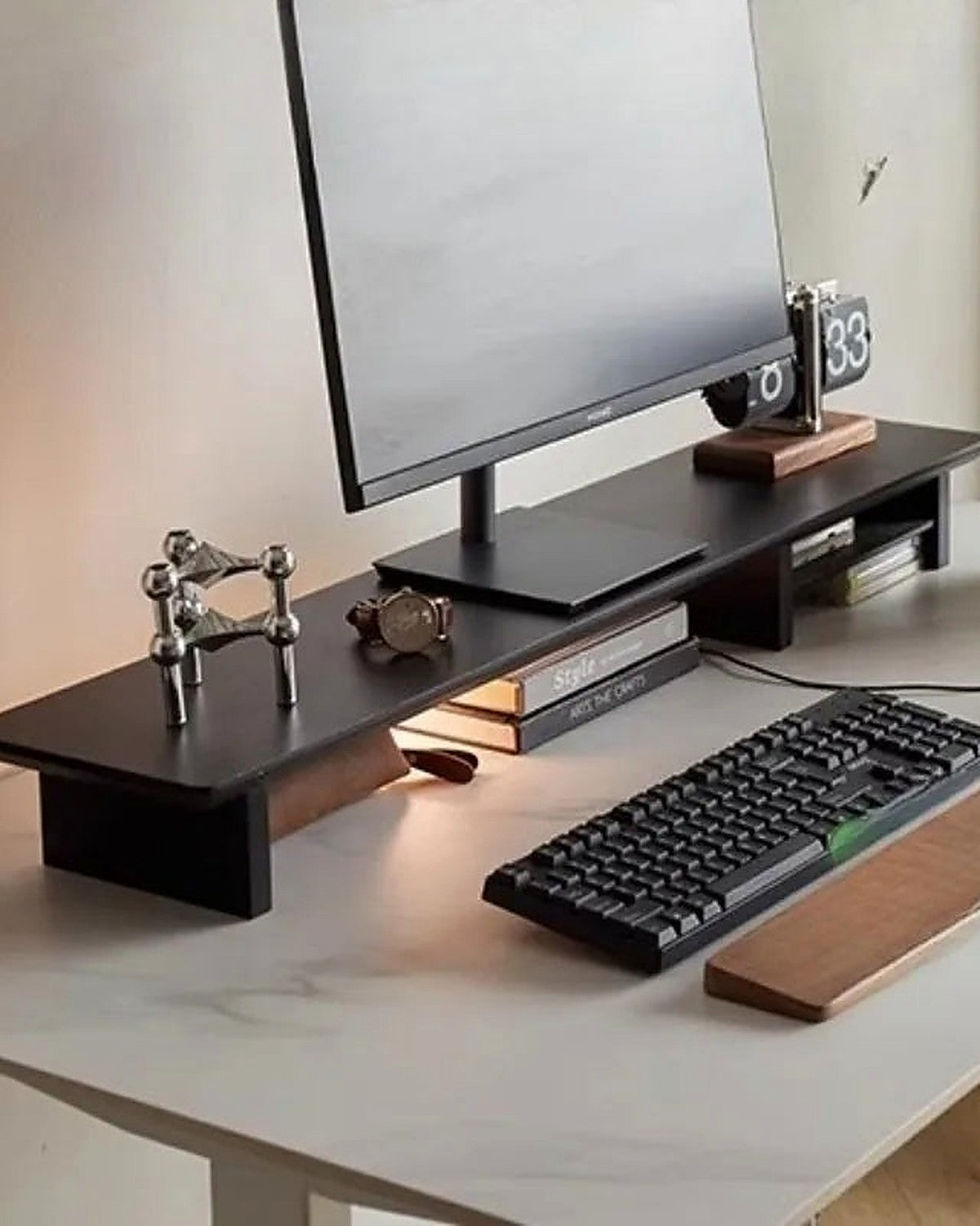 A blackwood monitor riser lifting a monitor above a keyboard